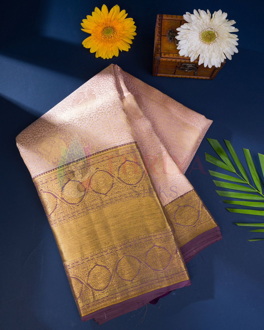 Folded pastel pink Kanjivaram saree with ornate gold zari border and pallu details