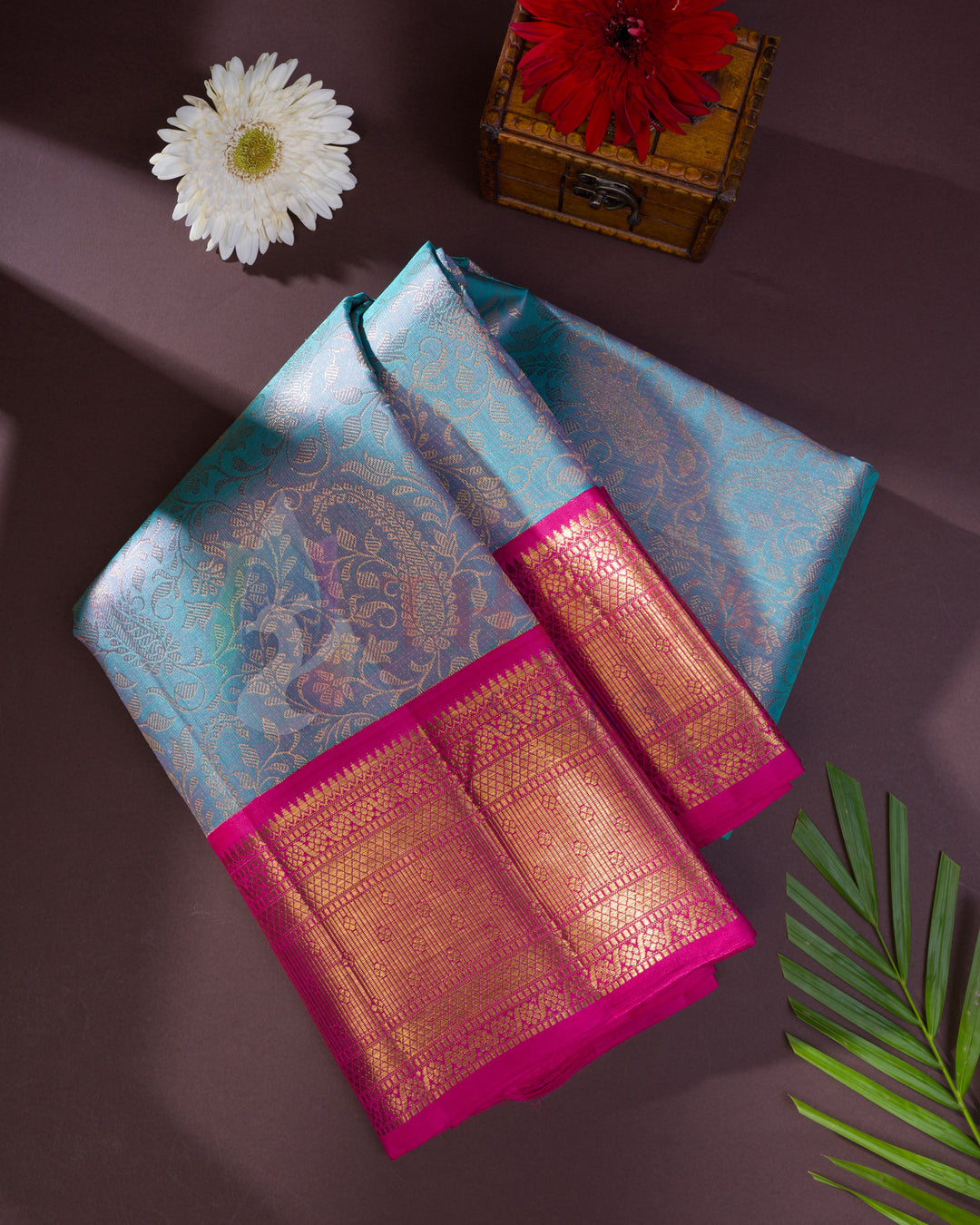 Folded pastel blue Kanjivaram silk saree with bright pink and gold zari floral pallu