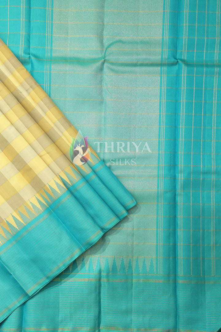 Pallu view of aqua blue silk saree with vertical zari stripes and yellow checks.