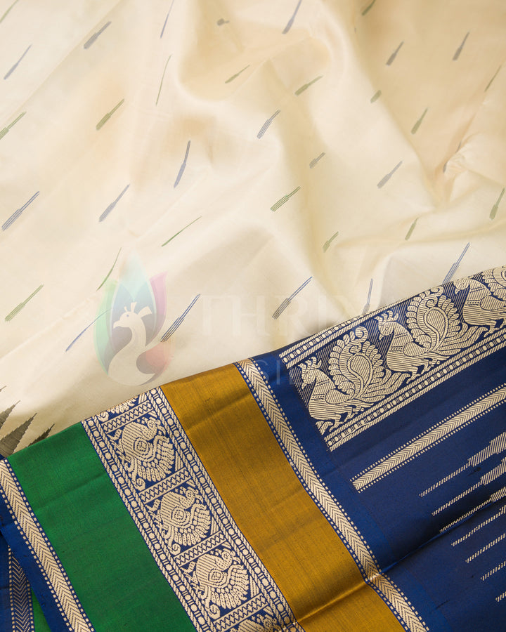 Close-up of cream silk saree with minimal motifs and traditional blue and gold pallu, Thriya Silks