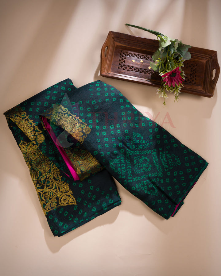 Folded black green Kanchipuram silk saree showcasing pink zari border and golden motifs
