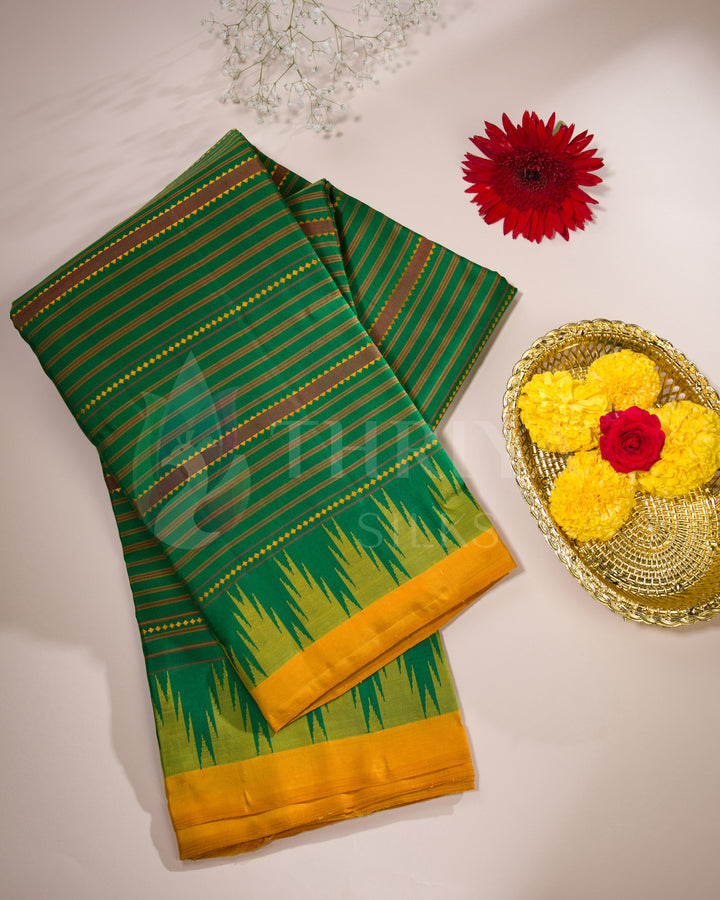 Folded green and yellow silk saree displayed with decorative flowers in a lifestyle setting, Thriya Silks