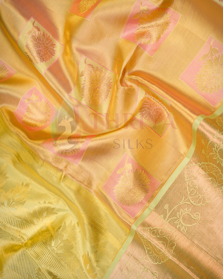 Close-up view of golden yellow Kanjivaram silk saree highlighting detailed green zari work and elegant pattern.