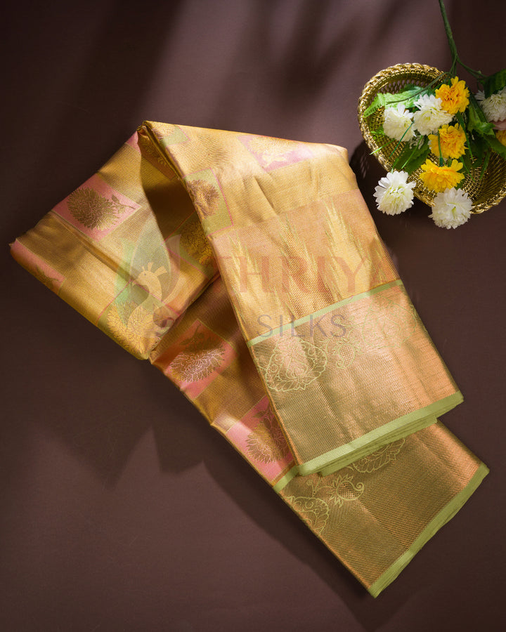 Golden yellow Kanjivaram silk saree folded neatly, featuring intricate green zari border and rich texture.