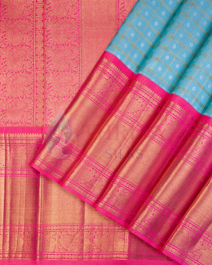 Folded Kanchipuram silk saree with pink body, sky blue pallu, and gold zari detailing