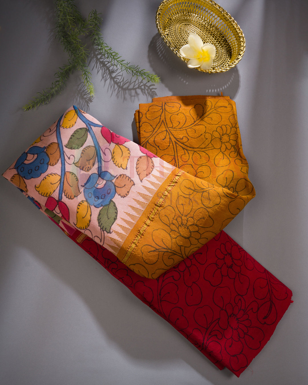 Folded view of handloom silk saree with red body, mustard pallu, and multicolor floral pattern