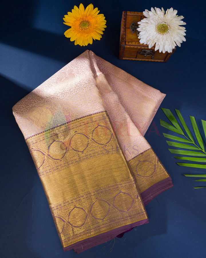 Folded pastel pink Kanjivaram saree with ornate gold zari border and pallu details