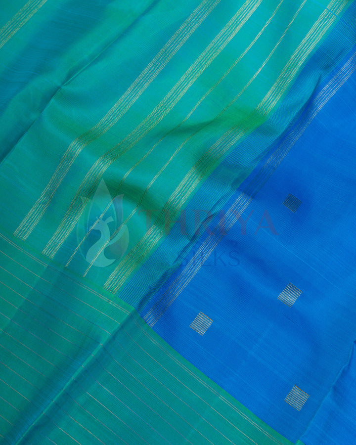 Close-up of blue and green silk saree with golden zari striped border and small motifs