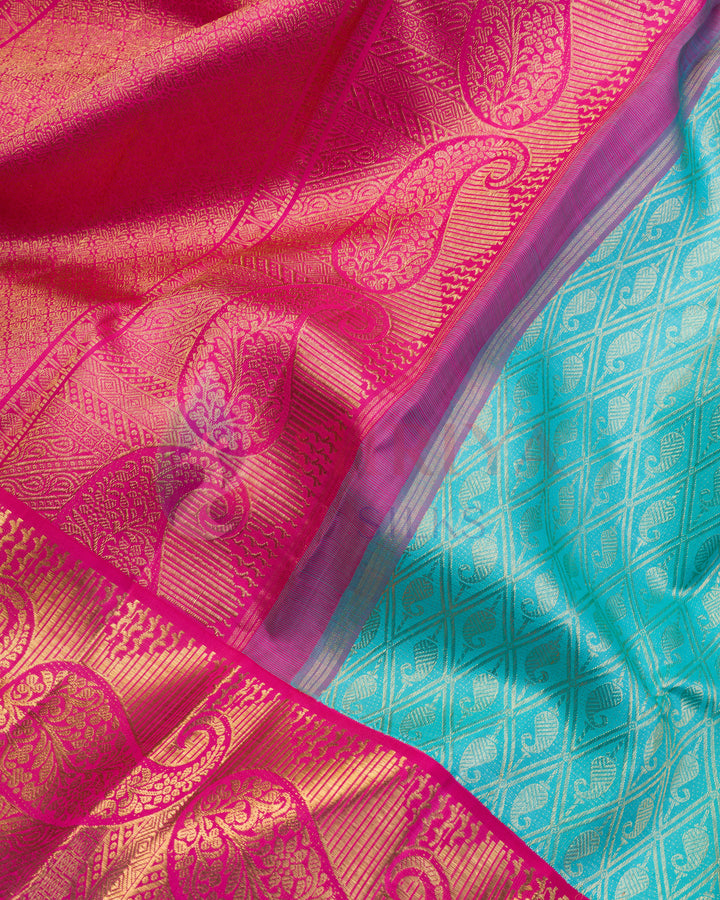 Detailed close-up of bright pink and gold zari paisley motifs on turquoise blue Kanjivaram silk saree pallu