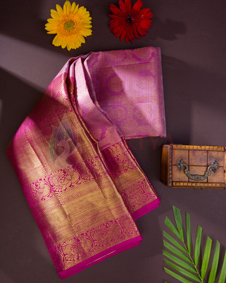 Folded pink Kanjivaram silk saree with rich golden zari pallu and floral designs – flatlay styling