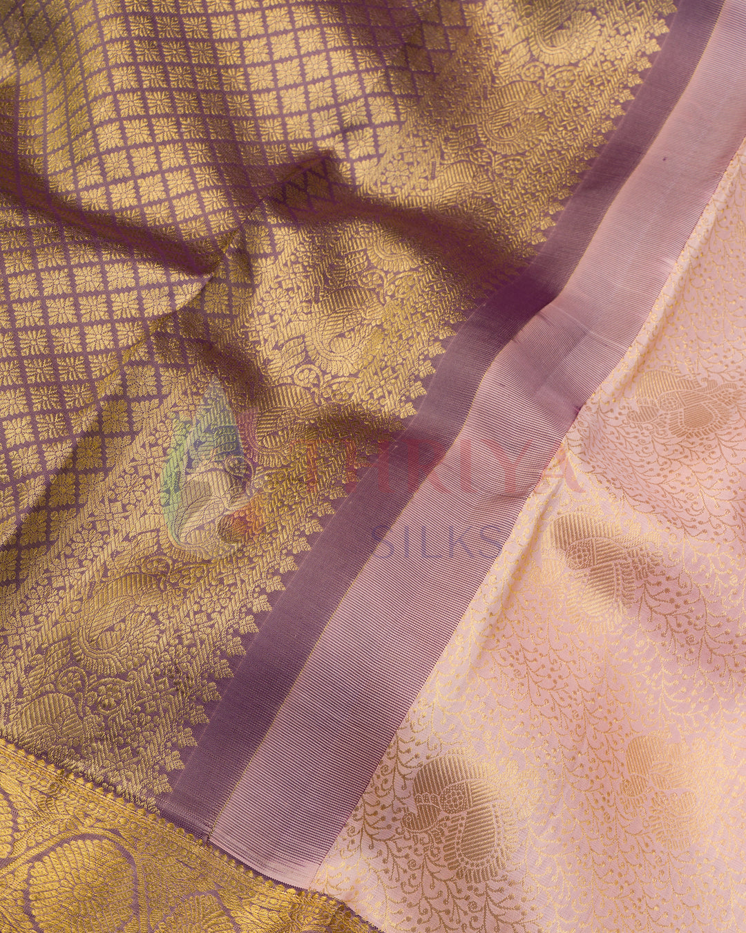 Close-up of purple zari border with traditional motifs on pastel pink silk fabric