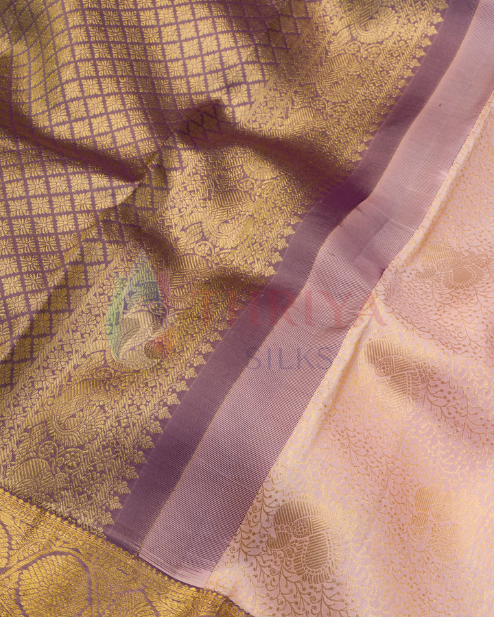 Close-up of purple zari border with traditional motifs on pastel pink silk fabric