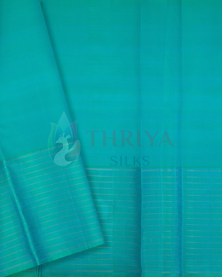 Green silk blouse piece with golden zari striped border complementing blue saree