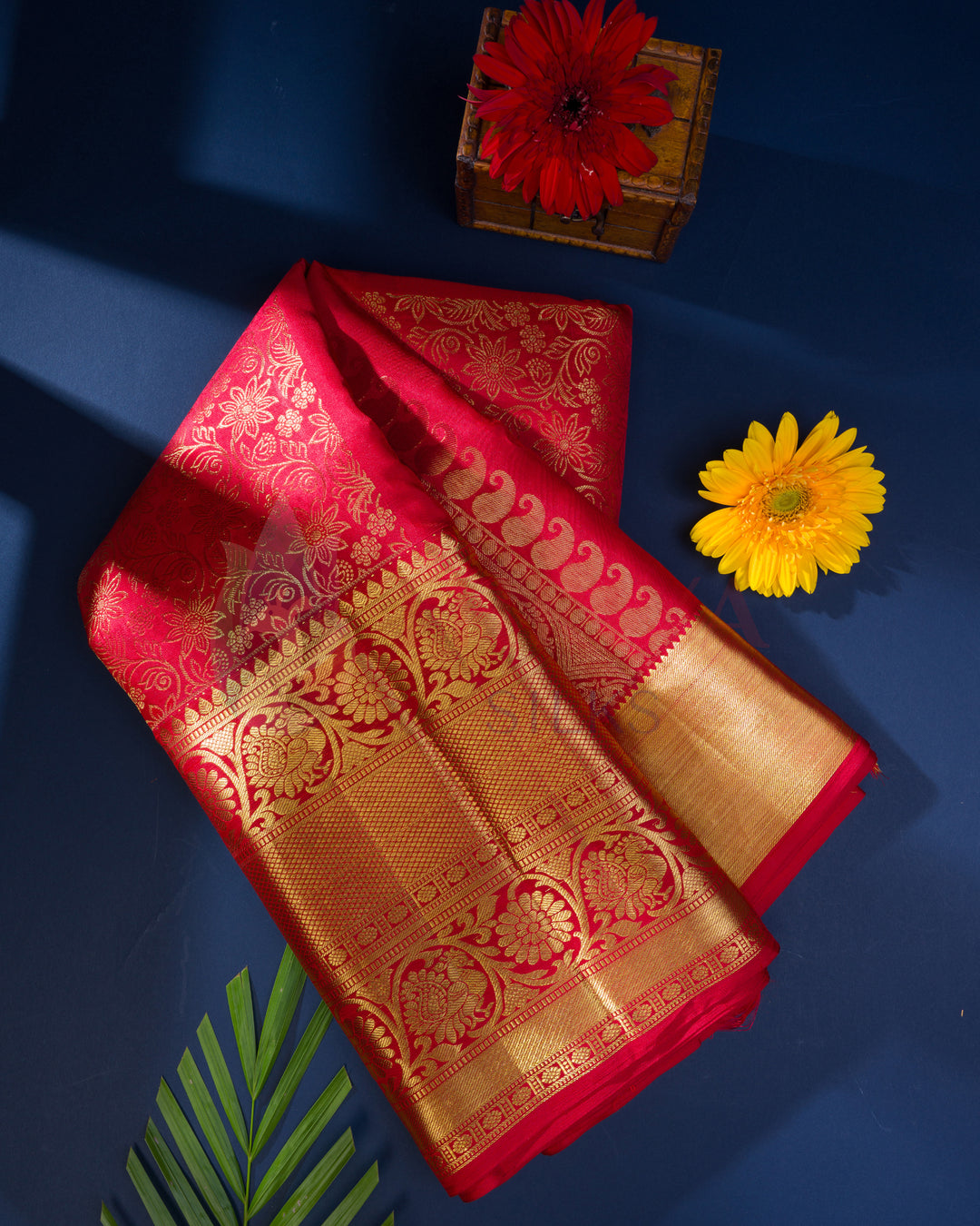 Folded red Kanjivaram silk saree with traditional golden zari pallu, ideal for weddings or festivals