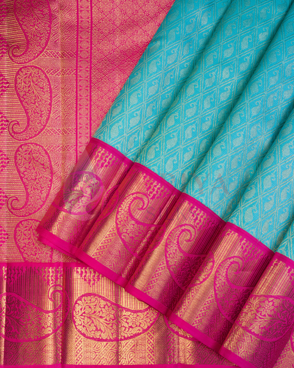 Turquoise blue Kanjivaram silk saree with bright pink border adorned with intricate golden paisley zari work