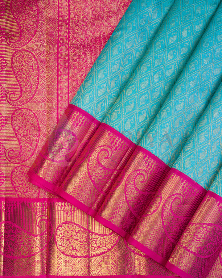 Turquoise blue Kanjivaram silk saree with bright pink border adorned with intricate golden paisley zari work
