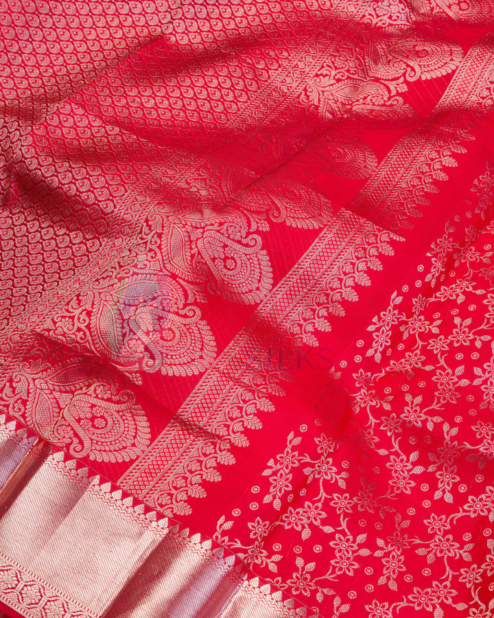 Detailed silver zari weaving on red silk Kanjivaram saree with intricate flower patterns