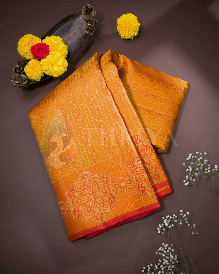Folded Banarasi silk saree in golden yellow with red floral zari border, styled with festive flowers