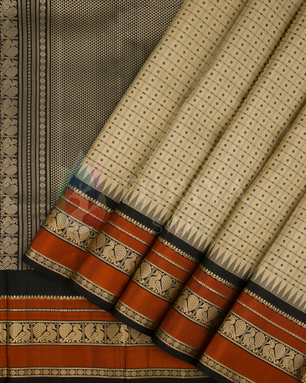 Beige silk saree with rust-orange and black zari border featuring traditional motifs from Thriya Silks