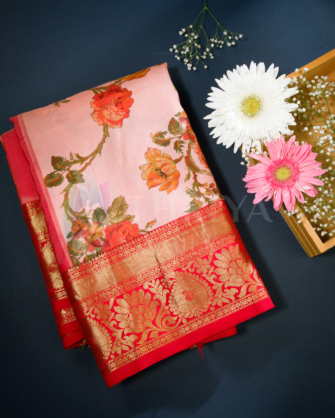 Folded view of blush pink Banarasi silk saree with vibrant floral motifs and a rich red zari border.