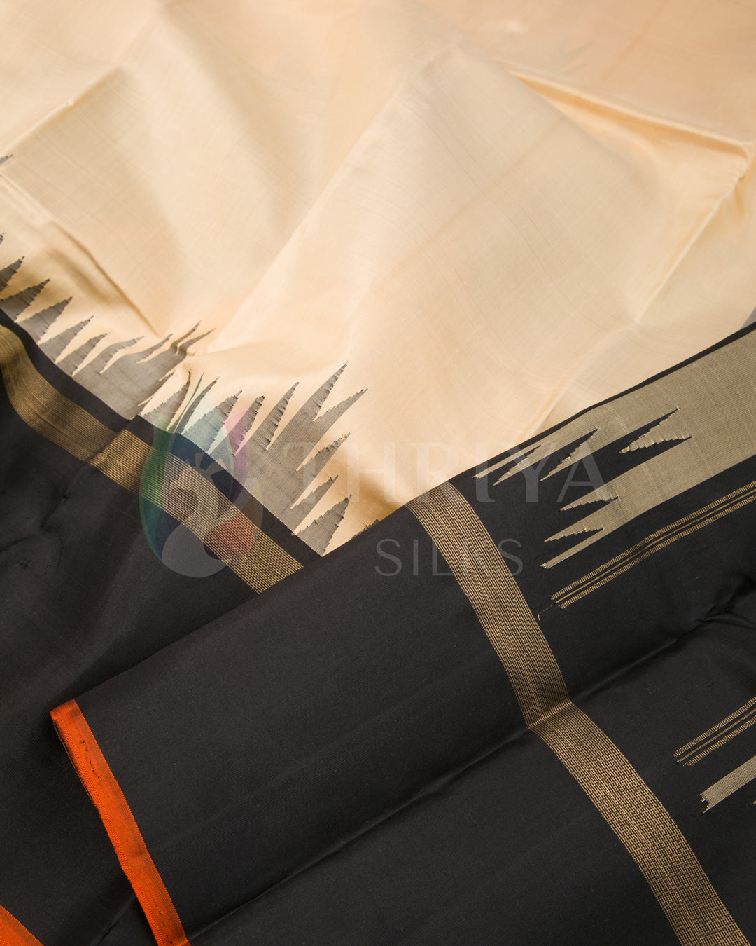 Close-up of beige silk saree with black temple border and subtle orange edge