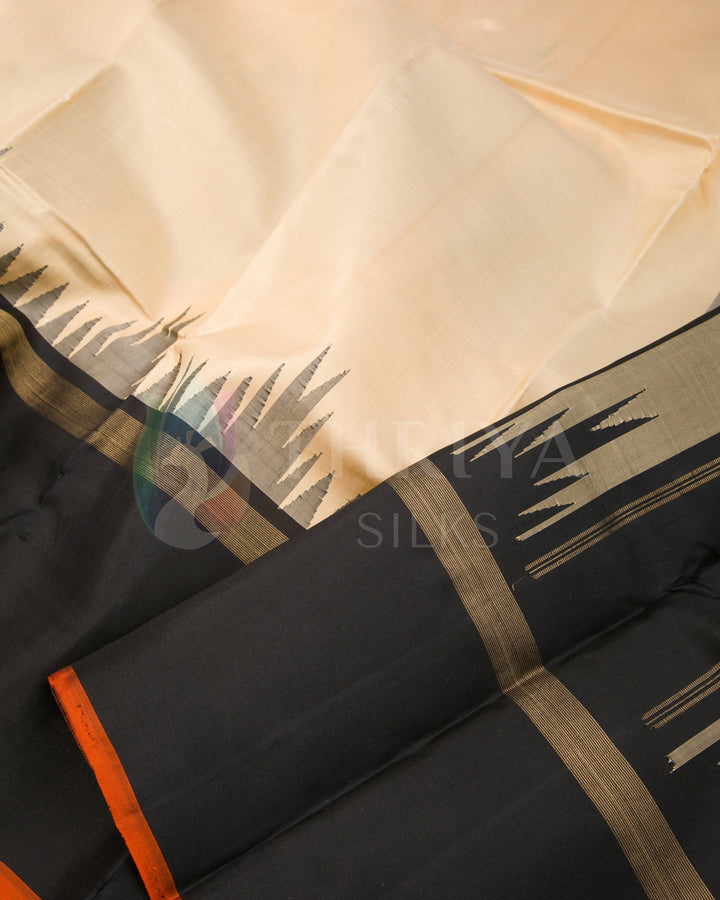Close-up of beige silk saree with black temple border and subtle orange edge