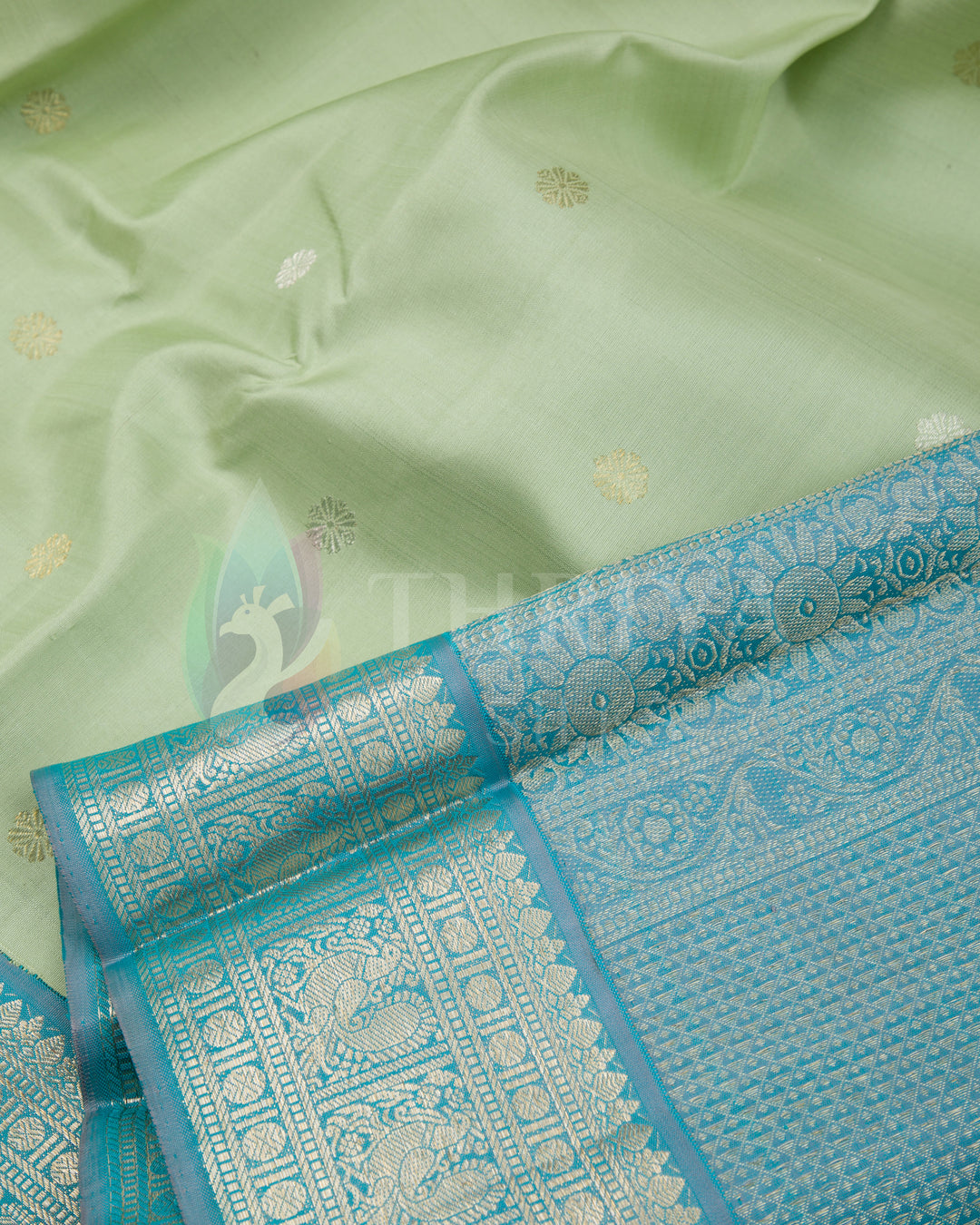 Close-up of pastel green silk saree with golden and silver buttas and intricate turquoise blue border