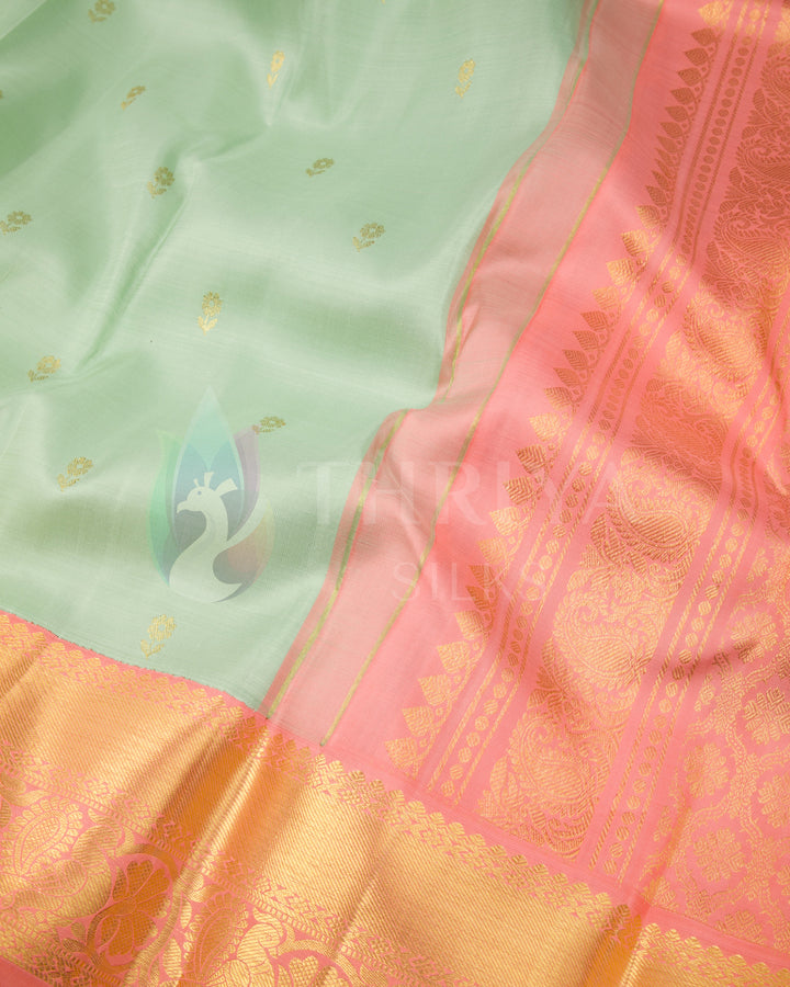 Close-up of pastel green saree body with gold buttas and peach-pink zari pallu