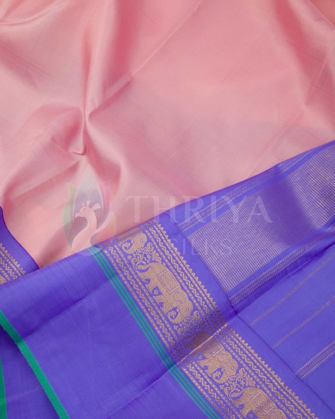 Close-up of peach pink Kanjivaram silk saree featuring violet border with golden motifs and green selvedge