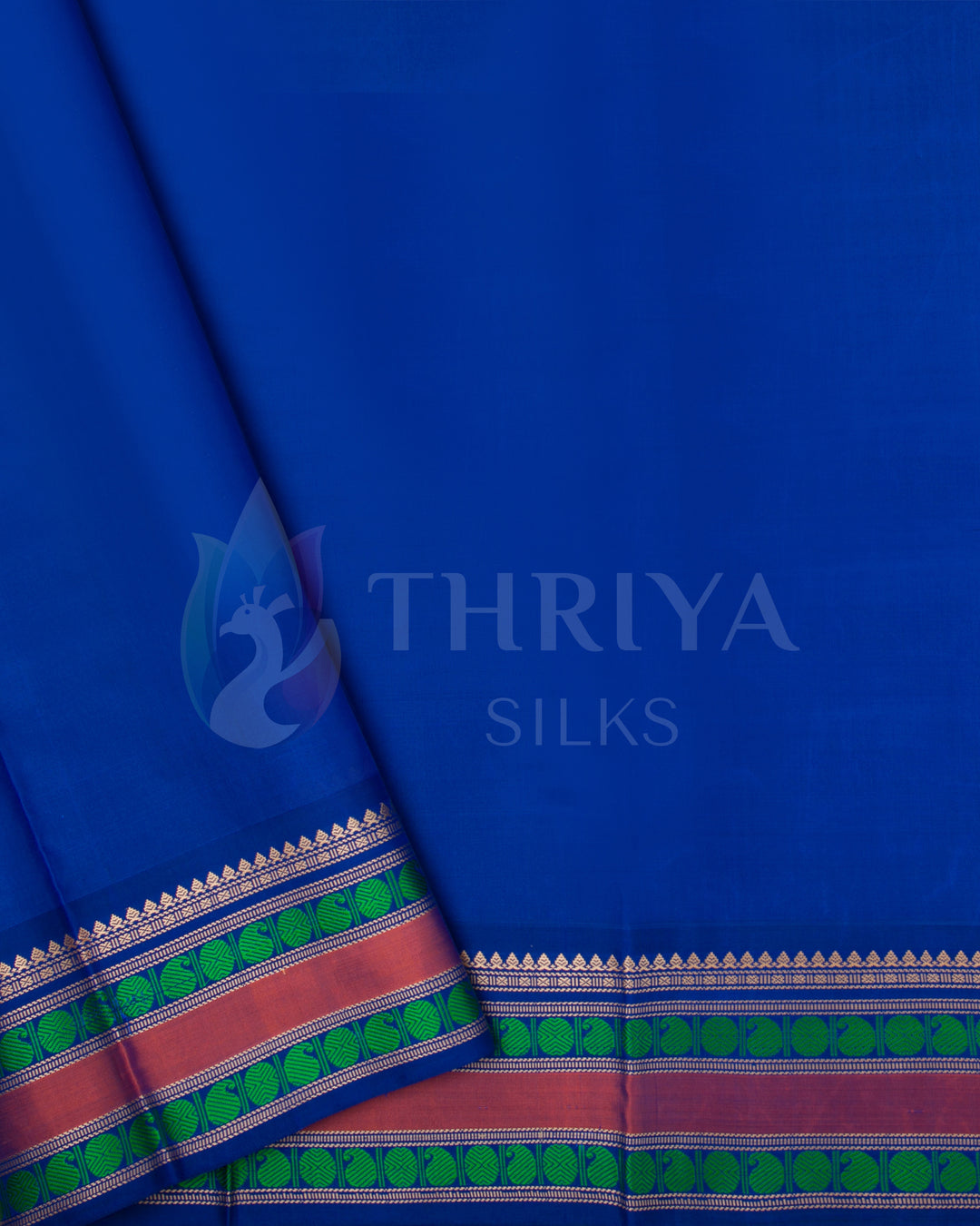 Contrasting royal blue blouse piece with pink and green zari border designed to match the green silk saree.
