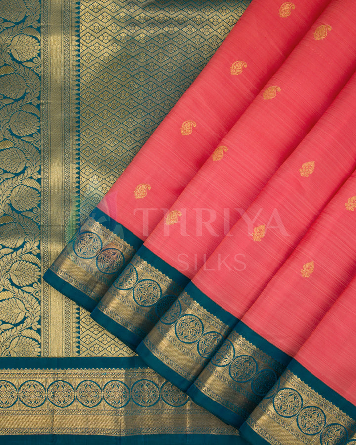Pleats of coral pink silk saree with gold paisley motifs and deep teal border with gold zari