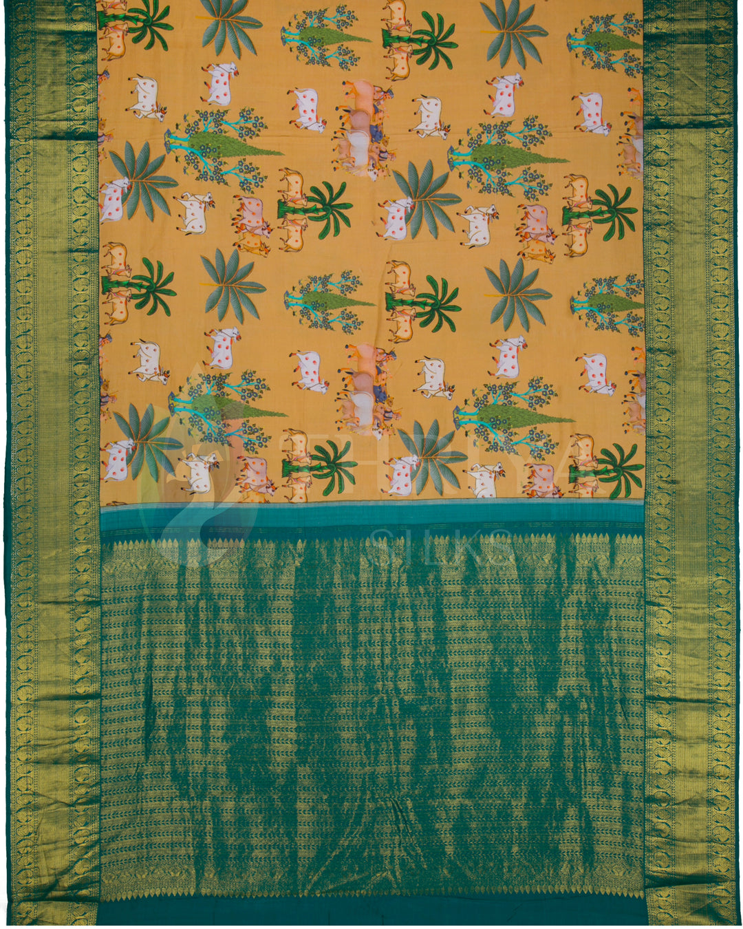 Full pallu view of the mustard silk saree with all-over cow and tree motifs and richly woven green zari pallu.