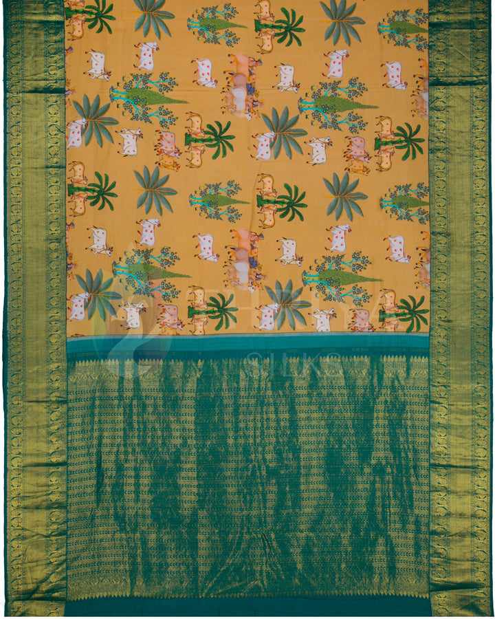 Full pallu view of the mustard silk saree with all-over cow and tree motifs and richly woven green zari pallu.