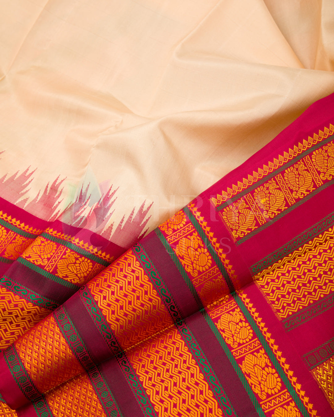 Close-up of cream silk saree fabric showing detailed pink, orange, and gold border work, Thriya Silks