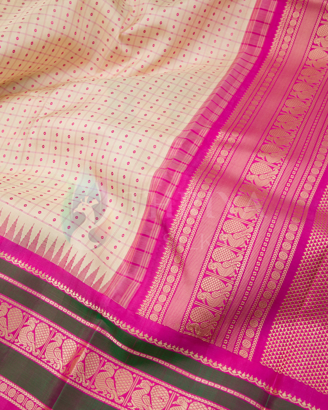 Close-up view of cream saree with intricate pink zari border and dotted pattern, Thriya Silks
