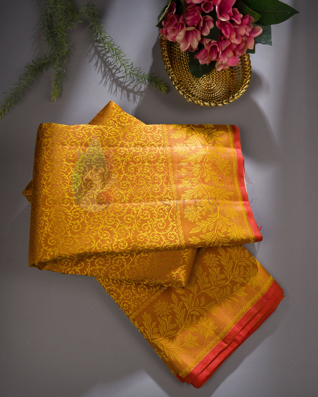 Yellow Kanjivaram silk saree with red zari border displayed with floral décor – traditional festive silk saree
