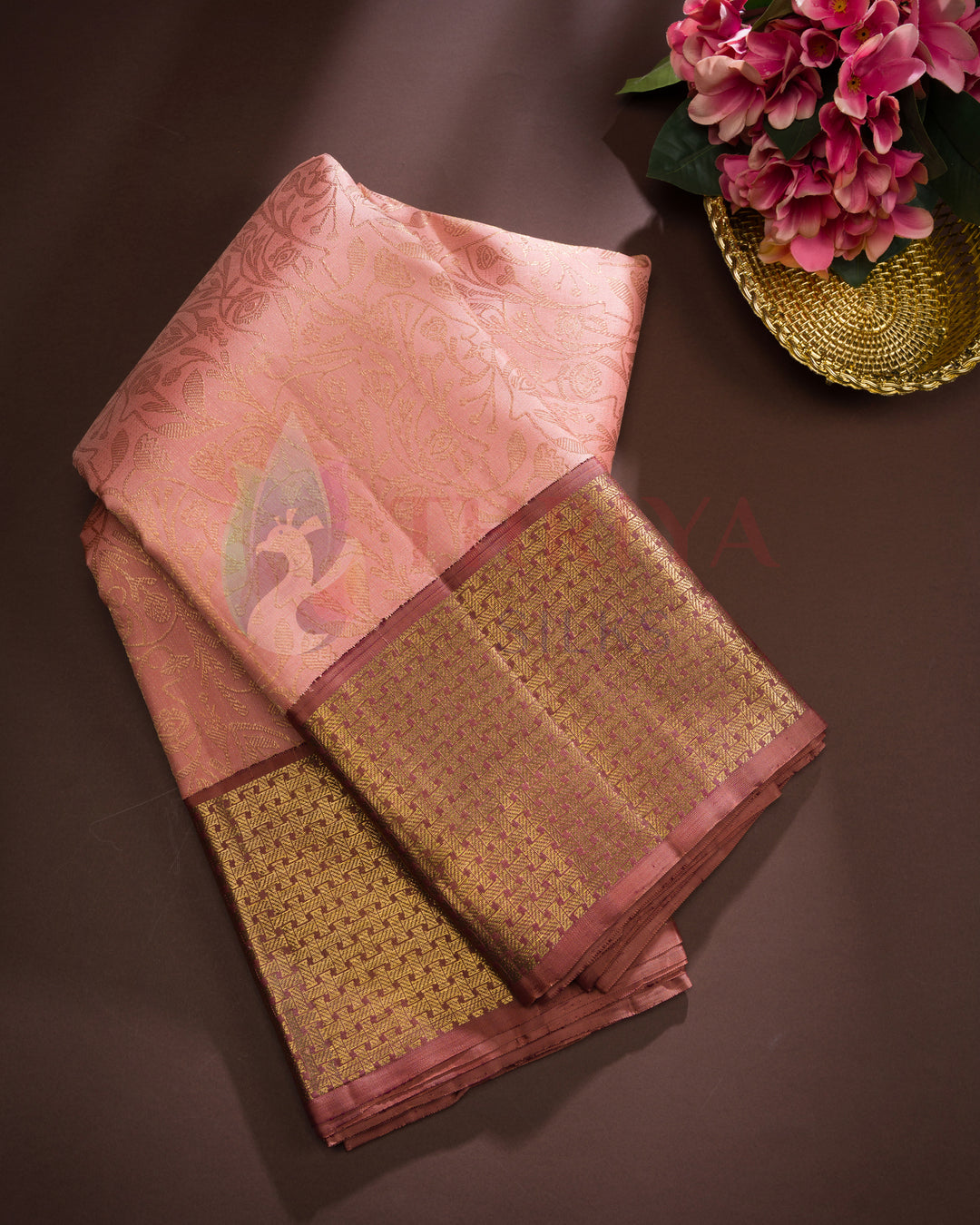 Folded dusty rose pink silk saree with intricate gold zari border and traditional weave – Thriya Silks