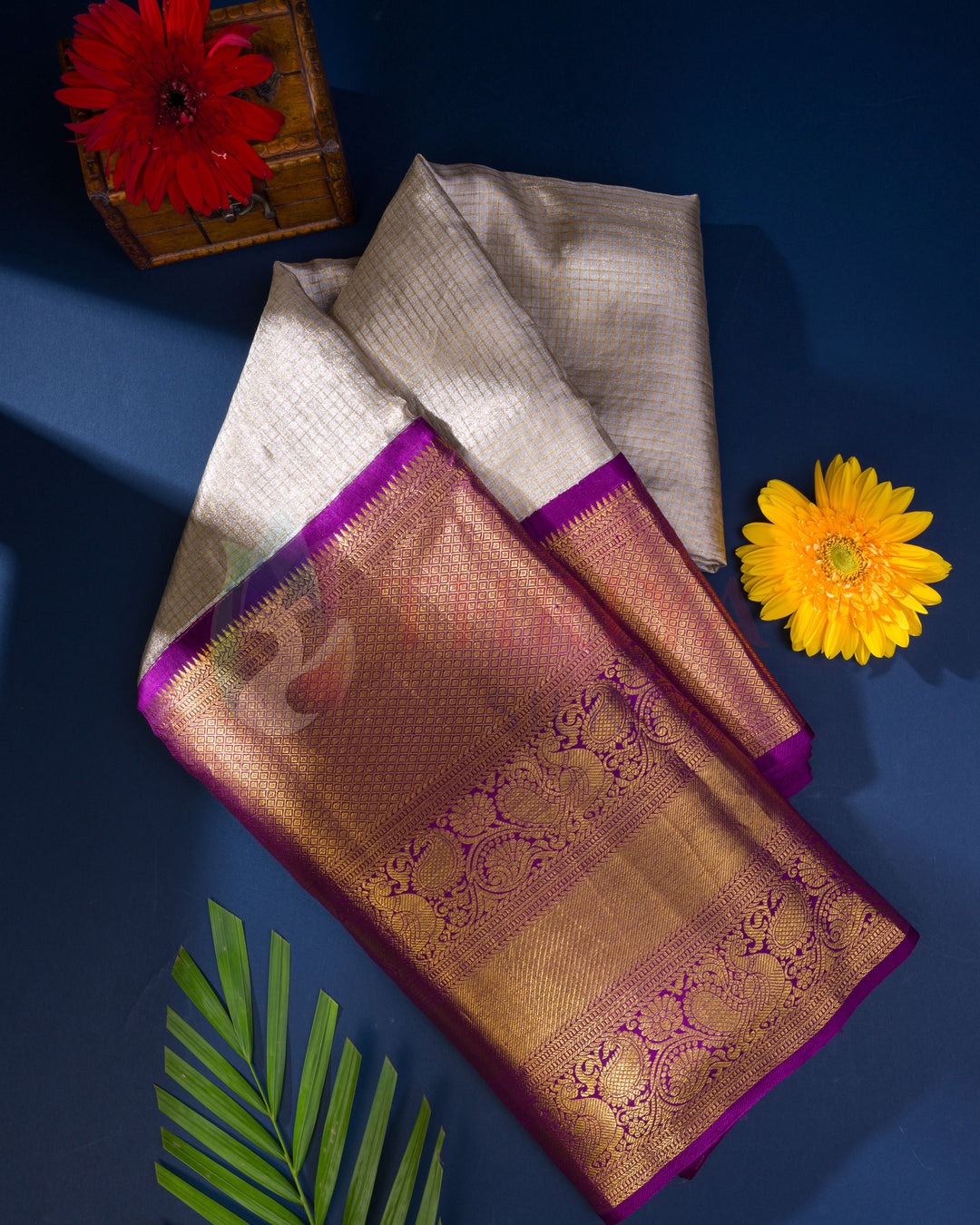 Folded cream Kanjivaram silk saree with rich purple and gold zari pallu, perfect for festive occasions
