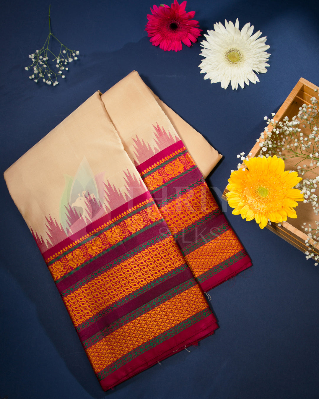 Folded cream and pink silk saree displayed with red, white, and yellow flowers, from Thriya Silks