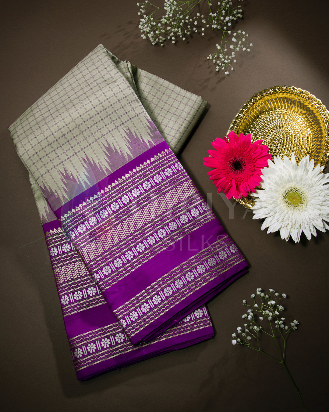 Folded olive green and purple Kanjivaram silk saree with silver zari work, styled with flowers