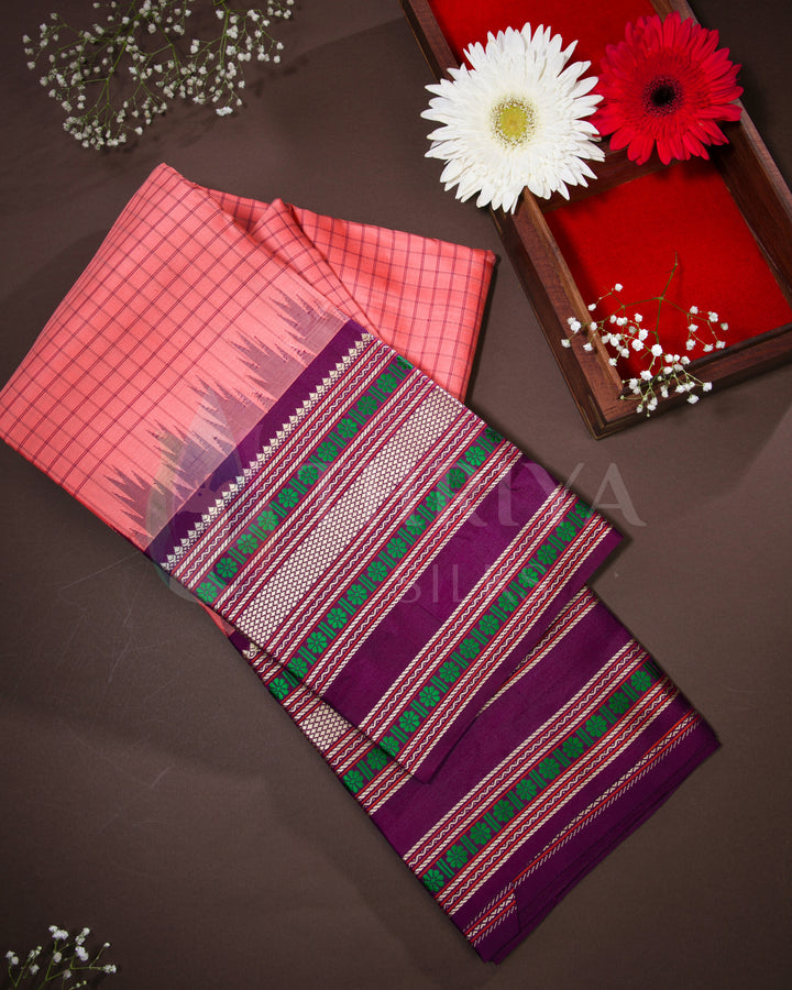 Folded peach and purple Kanjivaram silk saree with green zari work, styled with flowers
