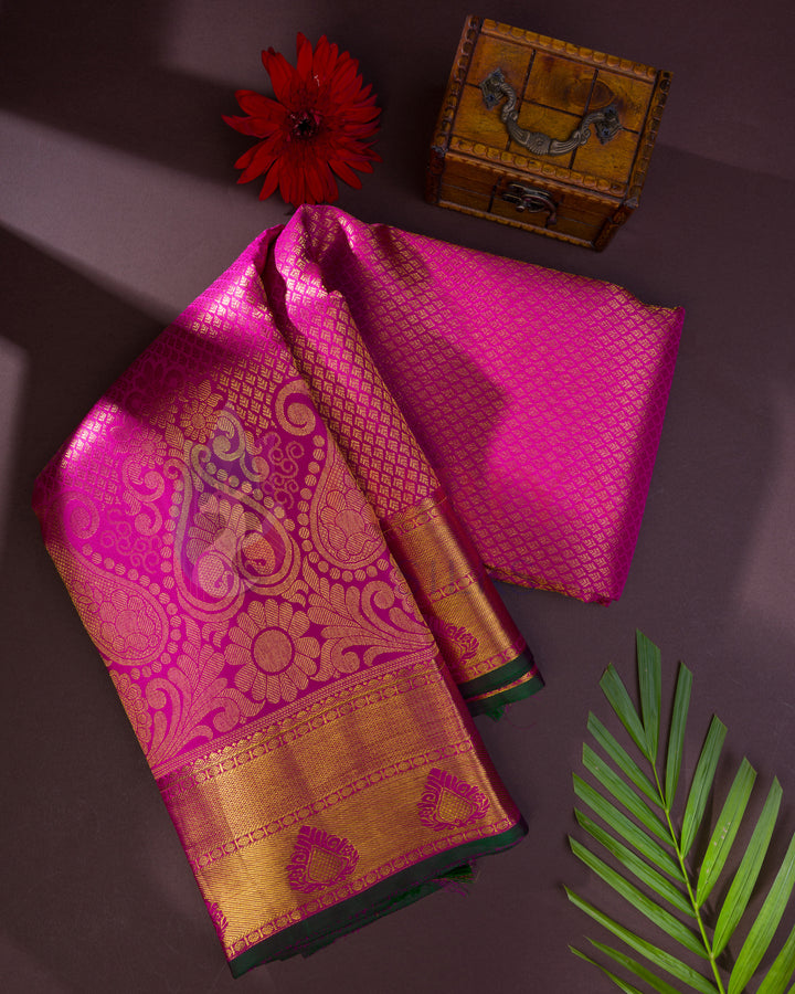 Folded pink silk saree with traditional mango buttas and golden pallu – styled flatlay