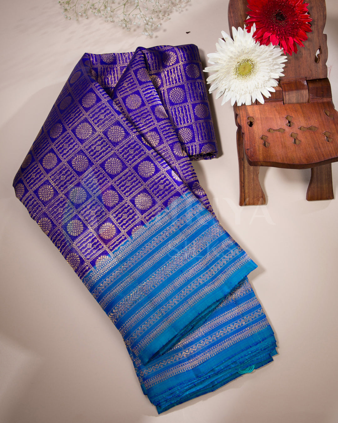 Folded purple and blue Kanjivaram silk saree with golden jacquard work styled with flowers