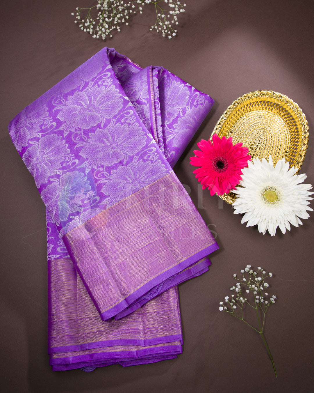 Folded purple Kanjivaram silk saree with golden border styled with flowers and golden tray