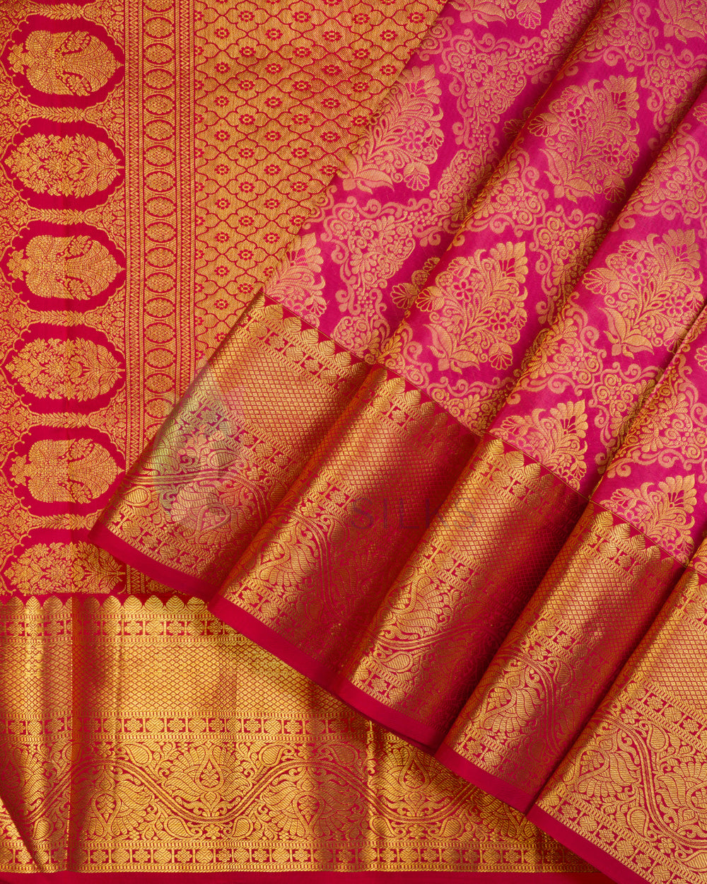 Folded rust Kanjivaram silk saree with rich gold zari border and traditional motifs