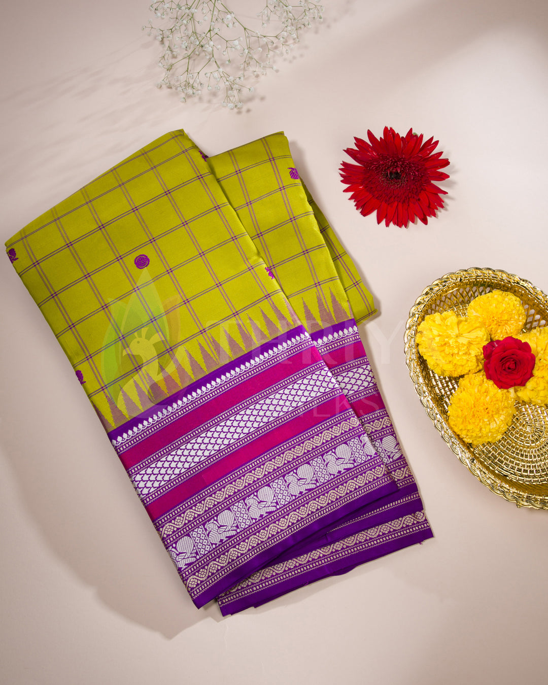 Folded yellow checked silk saree with magenta and silver zari border, styled with flowers, from Thriya Silks