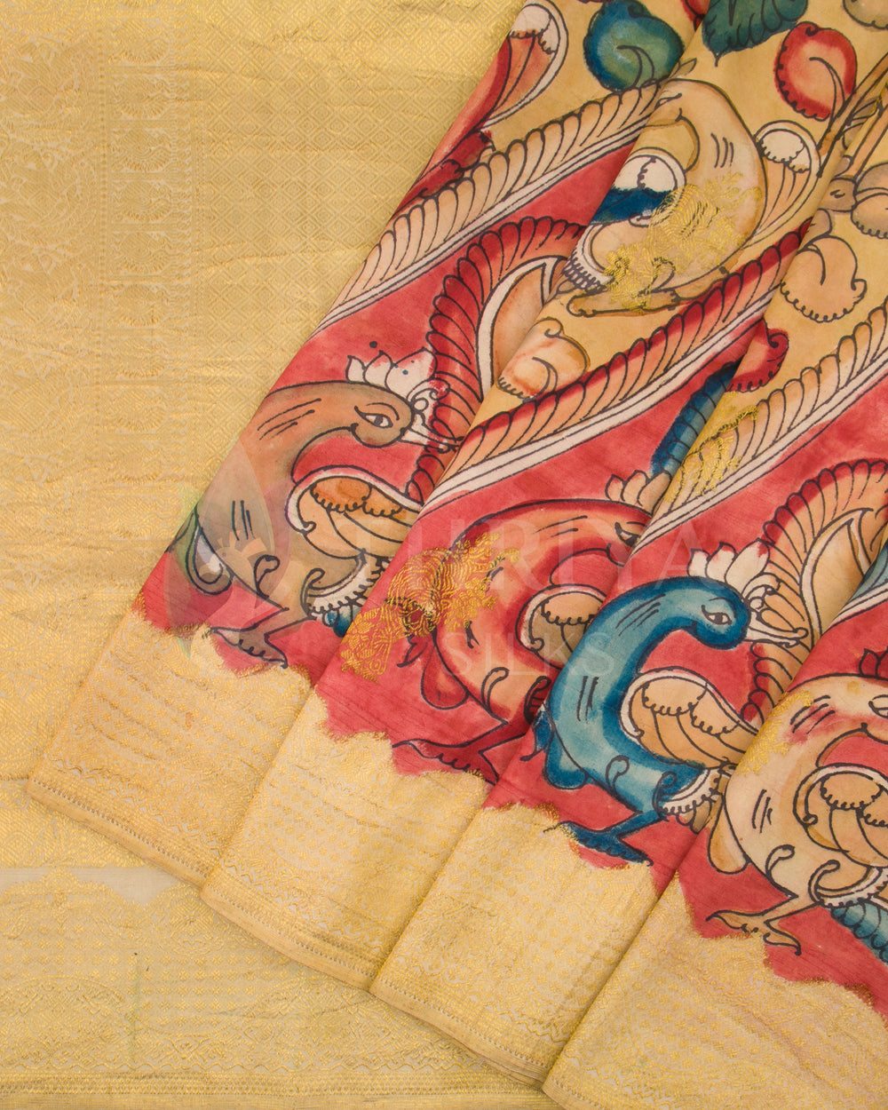 Close-up of saree pleats showing vibrant Kalamkari peacocks and detailed painting