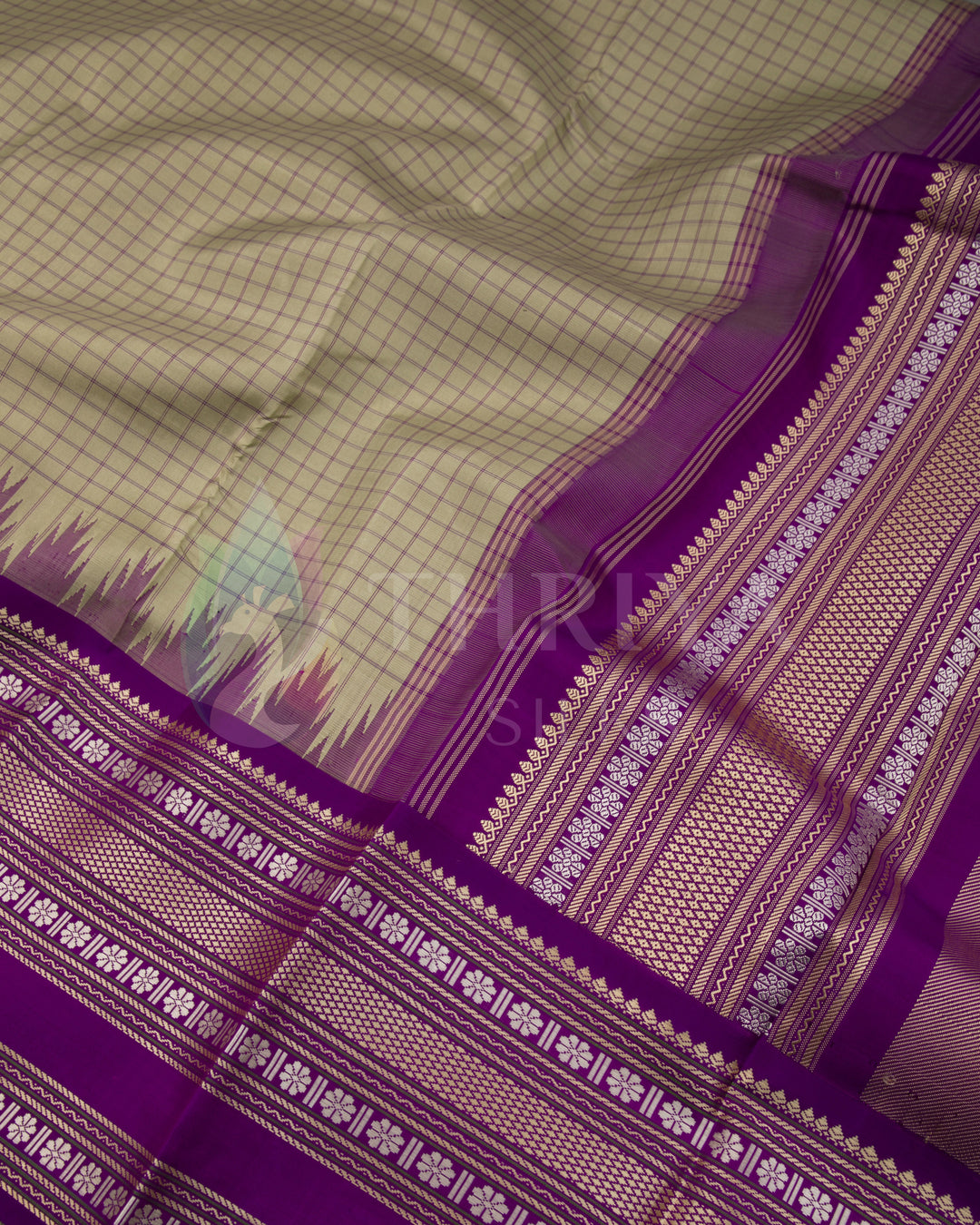 Close-up of olive green body with purple border and silver zari detailing in Kanjivaram saree