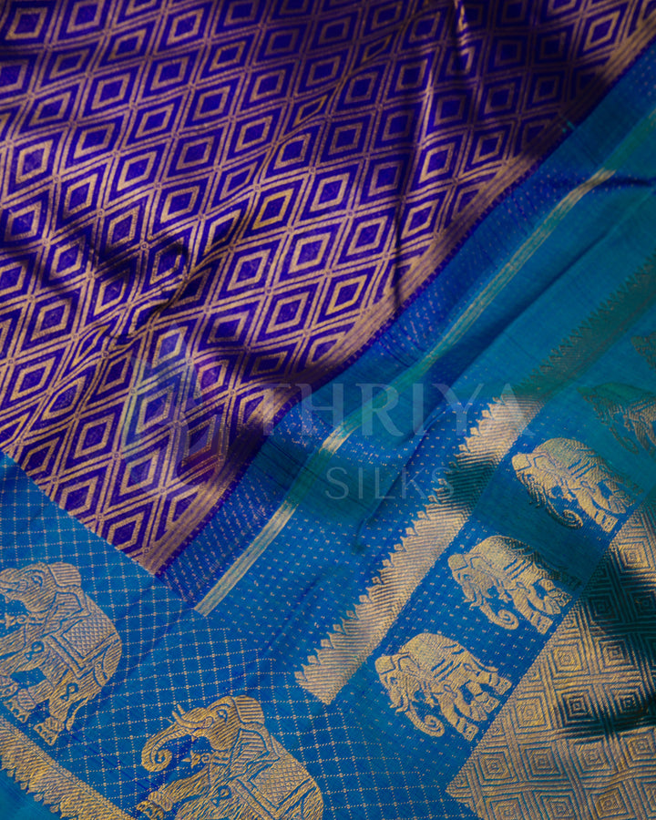 Close-up of purple silk saree with geometric zari patterns and bold peacock blue elephant border