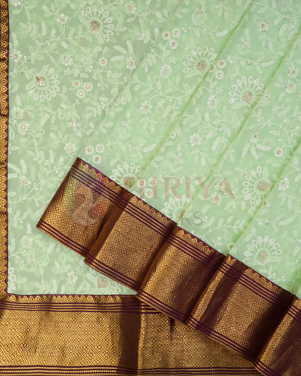 Light green Chikankari silk saree with floral motifs and gold-brown Kanchi border, folded view